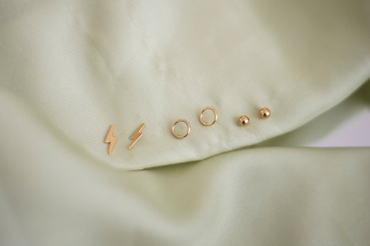 Minimal gold earrings flatlay on linen background
