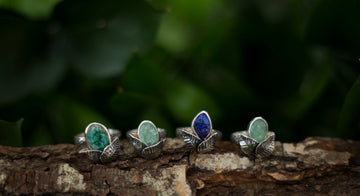 4 sterling silver rings on a wooden log.