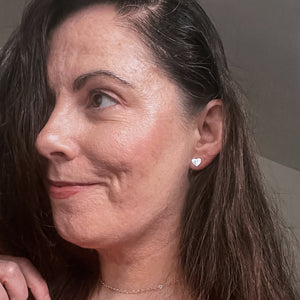 Side portrait picture of Elise wearing Amora heart studs and heart chain necklace