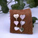 Close up juliet 2 heart drop earrings on leather square