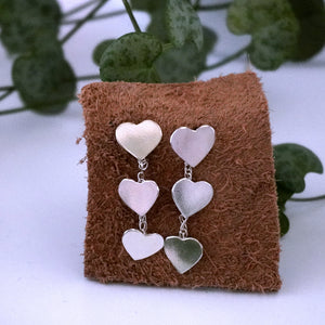 Close up juliet 2 heart drop earrings on leather square