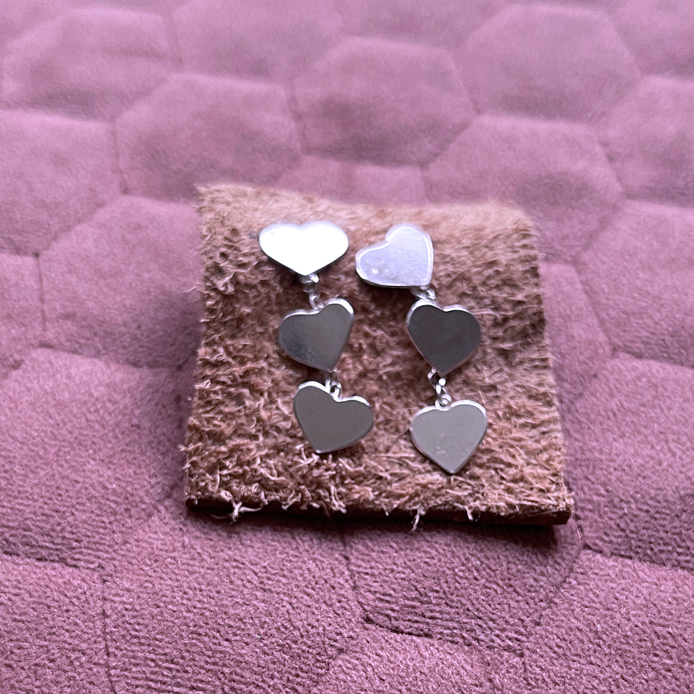 Close up juliet 2 heart drop earrings on leather square