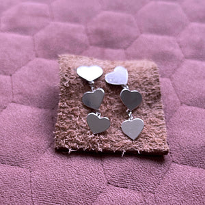 Close up juliet 2 heart drop earrings on leather square