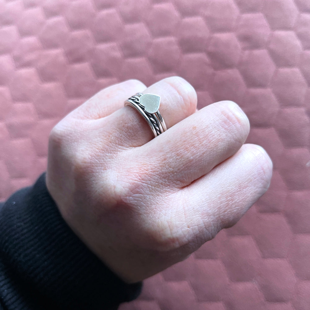 Vida heart ring and beau ring stacked together on ring finger of hand in a fist 