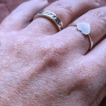 Flat hand close up showing beau ring in ring finger and vida heart ring on one to the right