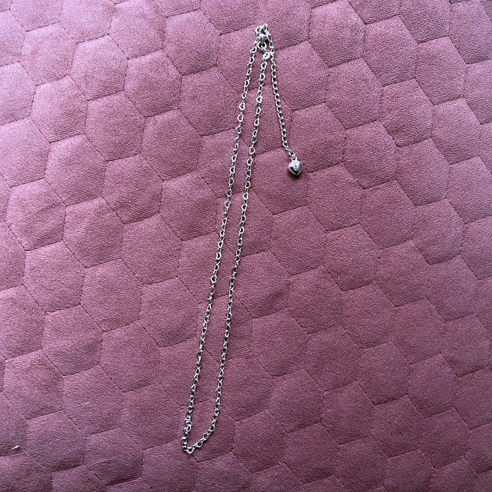 chain made of heart shapes connected together, lying on pink cushioned background