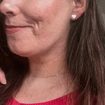Side portrait picture of Elise wearing Amora heart studs and heart chain necklace